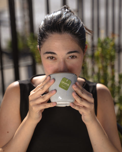 Woman enjoying Organsia tea in an urban garden